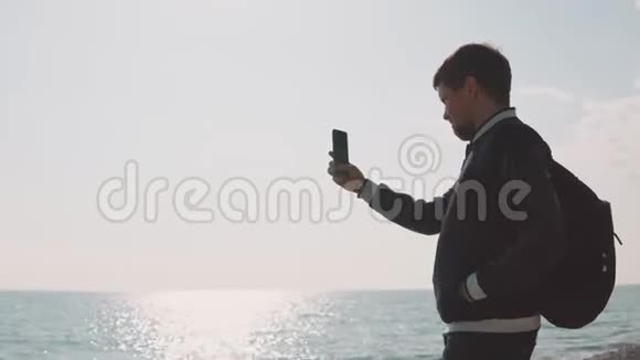 一位年轻的摄影师在智能手机上拍照一位绅士在海上视频的预览图