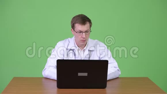 男医生坐着用笔记本电脑聊天问候病人视频的预览图