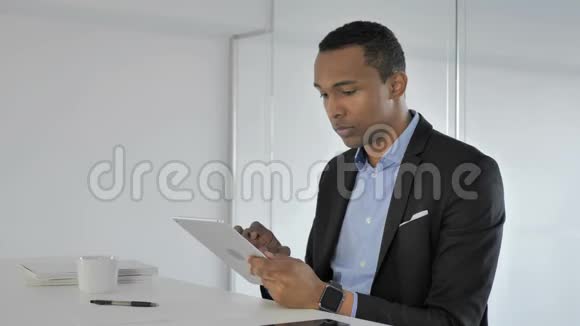 美国黑人商人在平板电脑上浏览互联网视频的预览图