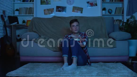 害怕的少年深夜看恐怖电影吃爆米花情绪视频的预览图