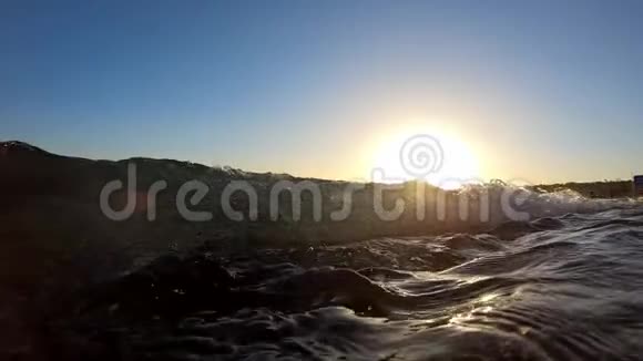 日落时分当海浪接近时相机潜入水中慢动作视频的预览图