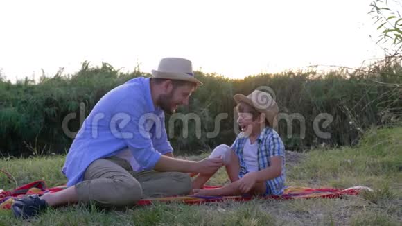 在乡下的一个家庭周末爸爸给儿子坐在地毯上受伤的膝盖绑上绷带视频的预览图