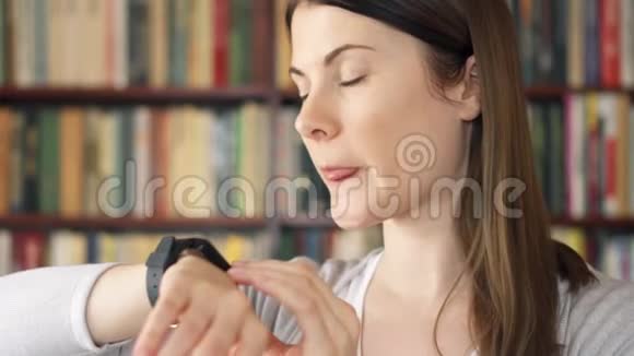 女大学生在图书馆使用智能手表通过信使向朋友口述音频信息视频的预览图