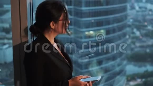 现代商务女性手里拿着智能手机在现代商务中心的大厅里视频的预览图