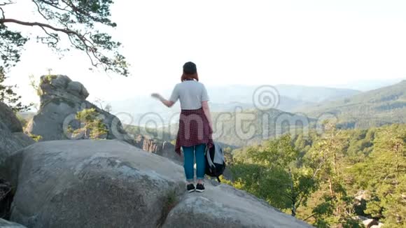 一位女士举着双臂站在山顶看着风景远足的女孩举起手臂庆祝风景视频的预览图