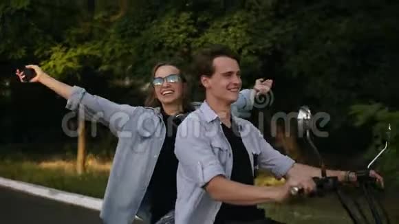快乐微笑的夫妇在公园里骑电动自行车伸出双手的女孩尽情享受在户外闲逛视频的预览图