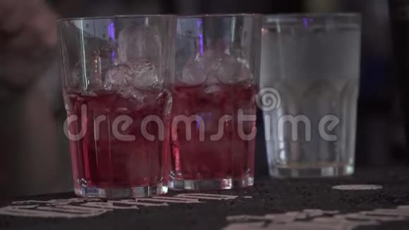 果汁被倒进站在酒吧的玻璃杯里酒保准备鸡尾酒特写视频的预览图