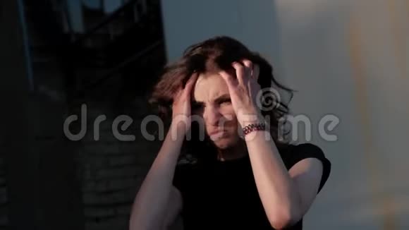 一个年轻的女人站在废弃的工厂前表情地解开她的头发哭泣感到内疚视频的预览图