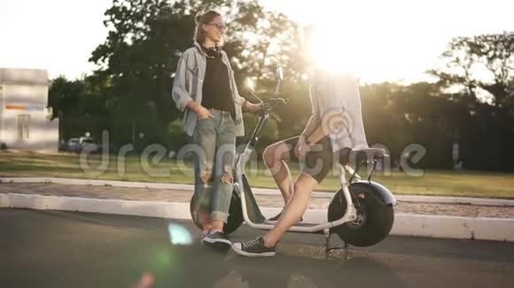 年轻的美女男孩和女孩在马路上的自行车附近年轻的女性正坐在自行车上调情视频的预览图