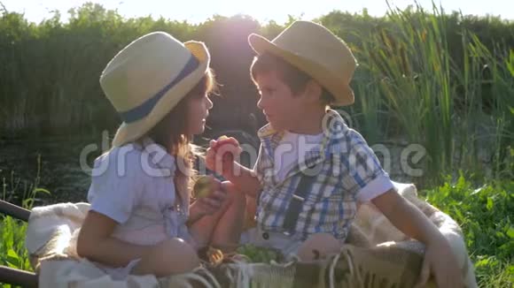 初恋两个孩子吃苹果在乡村日落的背景下坐在手推车里玩得开心视频的预览图