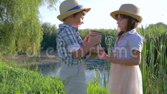 口渴的孩子喝着水壶里的水在湖边的阳光明媚的日子里大笑视频的预览图