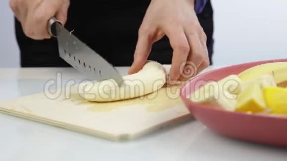 女人手拿刀在木厨房板上切香蕉视频的预览图