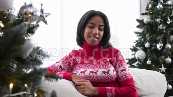 坐在圣诞树旁边沙发上的少女视频的预览图