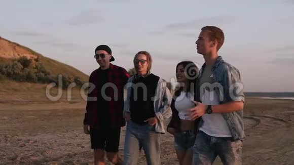 一群年轻人在海边或湖边的沙地路上散步微笑交流年轻夫妇穿着休闲服视频的预览图