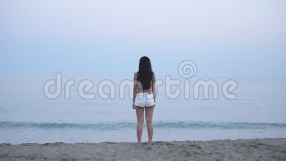 站在海滩边的年轻亚洲旅游妇女的后景视频的预览图