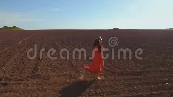 穿着红色长裙的年轻无忧无虑的女人在犁田里奔跑视频的预览图