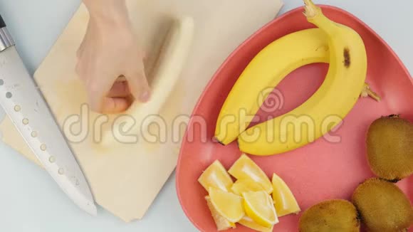 女人手在木制的厨房板上切香蕉上景4K视频的预览图