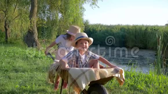 孩子们在户外玩耍小女孩拿着手推车和一个男孩在农村视频的预览图
