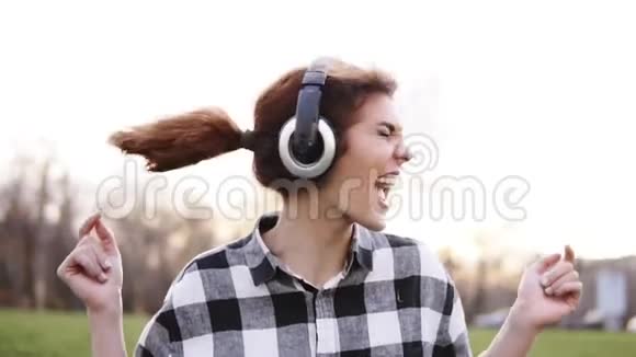 一个棕色头发的女孩非常有感情和表现力地挥舞着她的头听着耳机上的音乐舞蹈视频的预览图