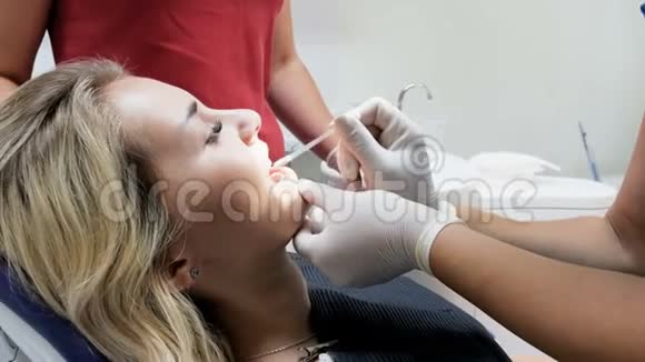 牙科医生用棉签从病人牙齿上取下口红特写镜头视频的预览图