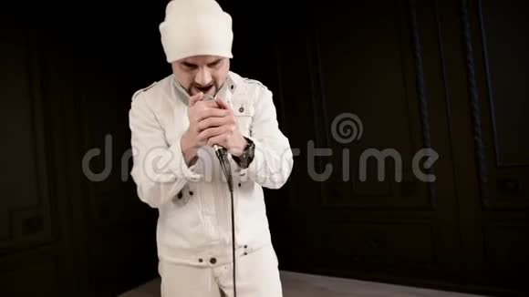 前台歌手摇滚流行乐留着时髦的胡须穿着白色衣服戴着帽子手里拿着麦克风视频的预览图