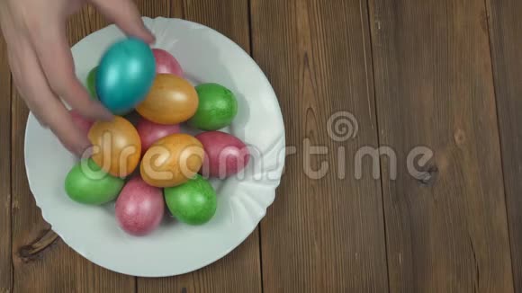 一个人在盘子木制背景复活节假期复印空间自制的彩色多色鸡蛋视频的预览图