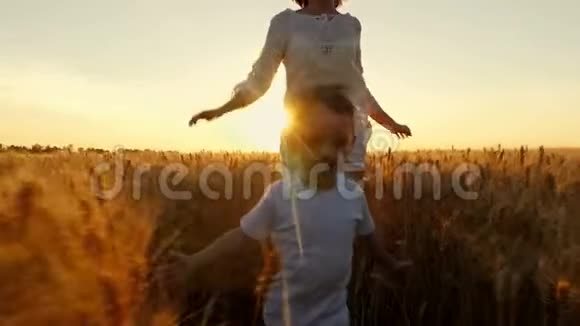 孩子和他的母亲正在夕阳的映衬下缓慢地在麦田里奔跑视频的预览图