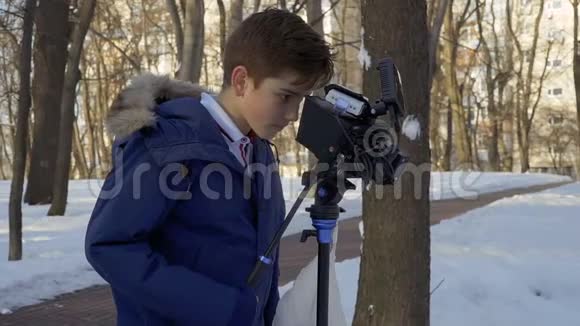 青少年在冬季公园学习用专业的摄像机拍摄电影视频的预览图
