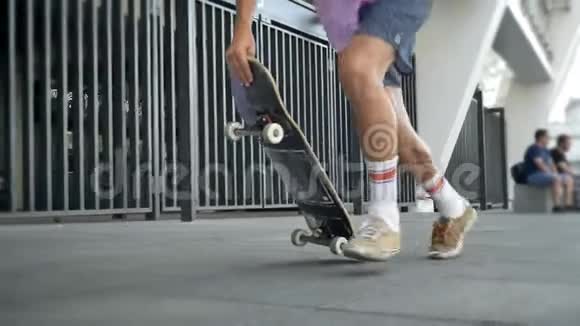 男腿在玩花样奥利在滑板滑板脚在城市滑冰从侧面观看视频的预览图