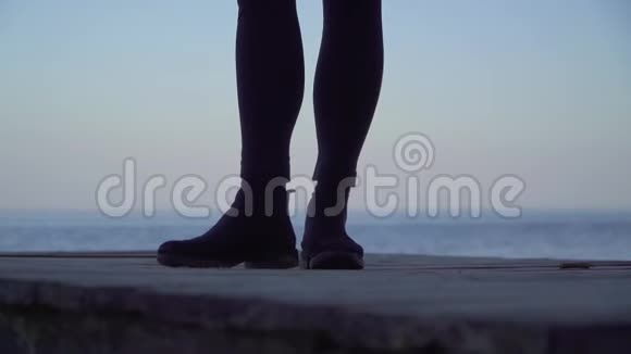 女性的腿站在户外的木制平台上穿紧身裤和靴子的女人的腿视频的预览图
