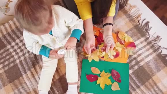 妈妈和小女儿用秋天的叶子做秋天的贴花带着妈妈的小女孩在秋天的秋天视频的预览图