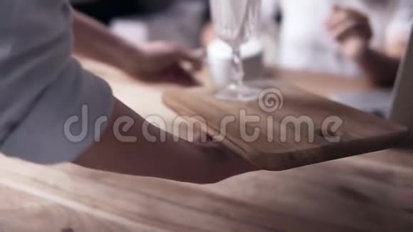 年轻的白衣美女坐在蓝色沙发上的咖啡馆里女服务员端来一杯茶放在桌上视频的预览图