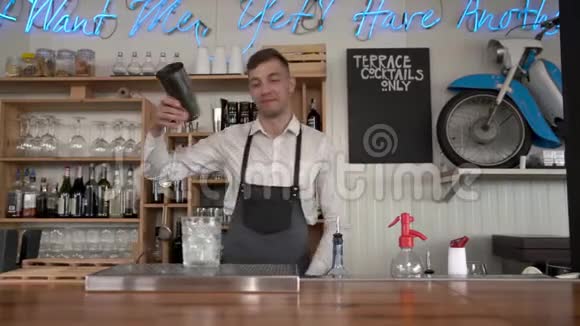有趣的微笑的酒保把一杯蓝色的库拉索酒倒入一个装有冰块的杯子里视频的预览图