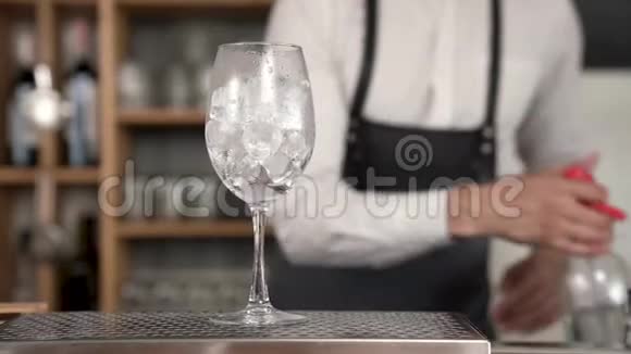 一位年轻英俊的酒保把汽水虹吸管里的一杯汽水倒进了装有冰块的杯子里视频的预览图