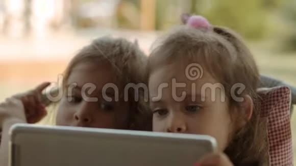 可爱的姐妹们拿着平板电脑看着上面的卡通视频的预览图