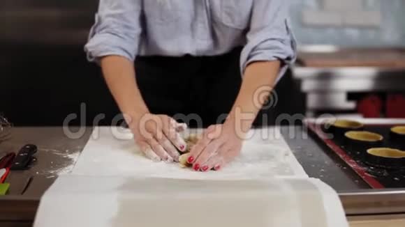 一个漂亮的白种人金发糖果师把糕点面团揉在工作表面微笑用手摇掉面粉视频的预览图