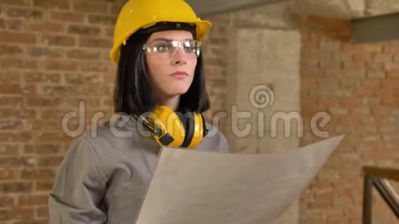 年轻迷人的建筑师女士拿着纸期待集中砖建筑背景视频的预览图