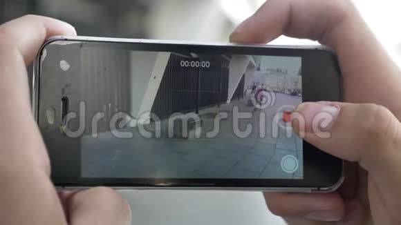 双手拿着智能手机在摄像机上拍摄年轻人在滑板上玩花样的视频视频的预览图