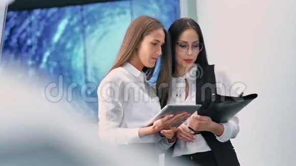 两位微笑迷人的女商人出席了Hitech数码显示技术展览会视频的预览图