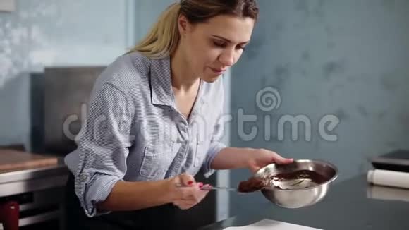 年轻女子糕点厨师在自己的厨房做甜点用勺子装满黑巧克力奶油的烤酒石视频的预览图