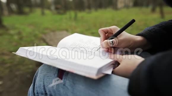 一个受启发的年轻女孩编了一个待办事项清单并把它写在一个坐在花园里的记事本上视频的预览图
