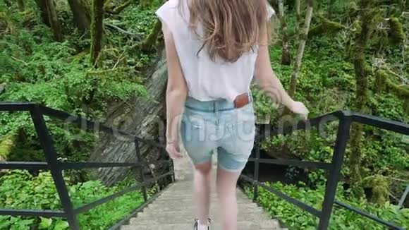 从后面看女孩在雨林里走下楼梯视频的预览图
