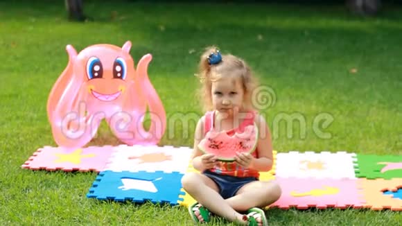 小女孩吃西瓜婴儿在夏天吃食物在绿草或草坪上野餐视频的预览图