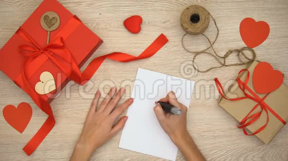 人在纸上画心签手工制作的礼品盒在木制背景上视频的预览图