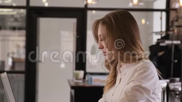 一个漂亮的金发女孩穿着一件白色的商业衬衫打开一台笔记本电脑开始工作的肖像一个年轻人视频的预览图