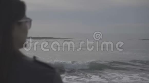 女人望着海浪冲刷沙滩海岸视频的预览图