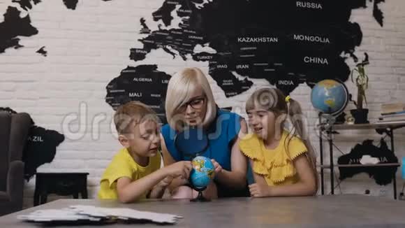 有两个孩子在地理课上看地球仪的老师可爱的男孩女孩和老师用视频的预览图