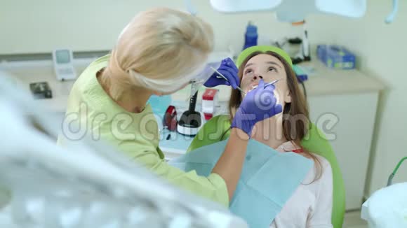 戴着医用手套检查病人牙齿的牙医牙科治疗女病人视频的预览图