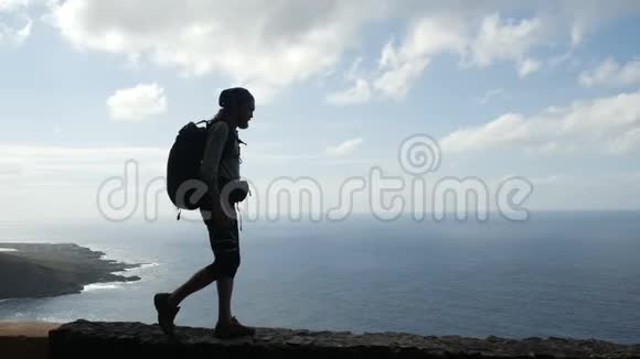 带背包的徒步旅行者正走在大洋上方加那利群岛的一条路的边缘特内利夫视频的预览图