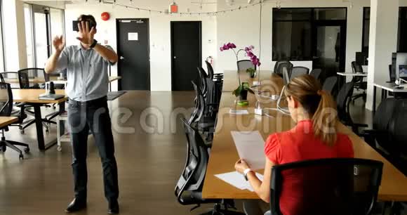 男高管使用虚拟现实耳机同事在办公桌前工作视频的预览图